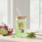 Glass jar with a wooden lid, filled with a green drink and lime slices, on a light surface with flowers and limes.