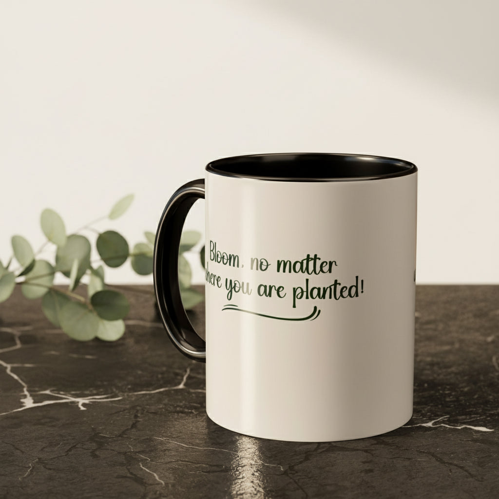 White mug with black interior and handle on a kitchen counter with text 'Bloom, no matter where you are planted!'.