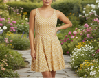 Woman in a yellow patterned dress standing in a garden with flowers