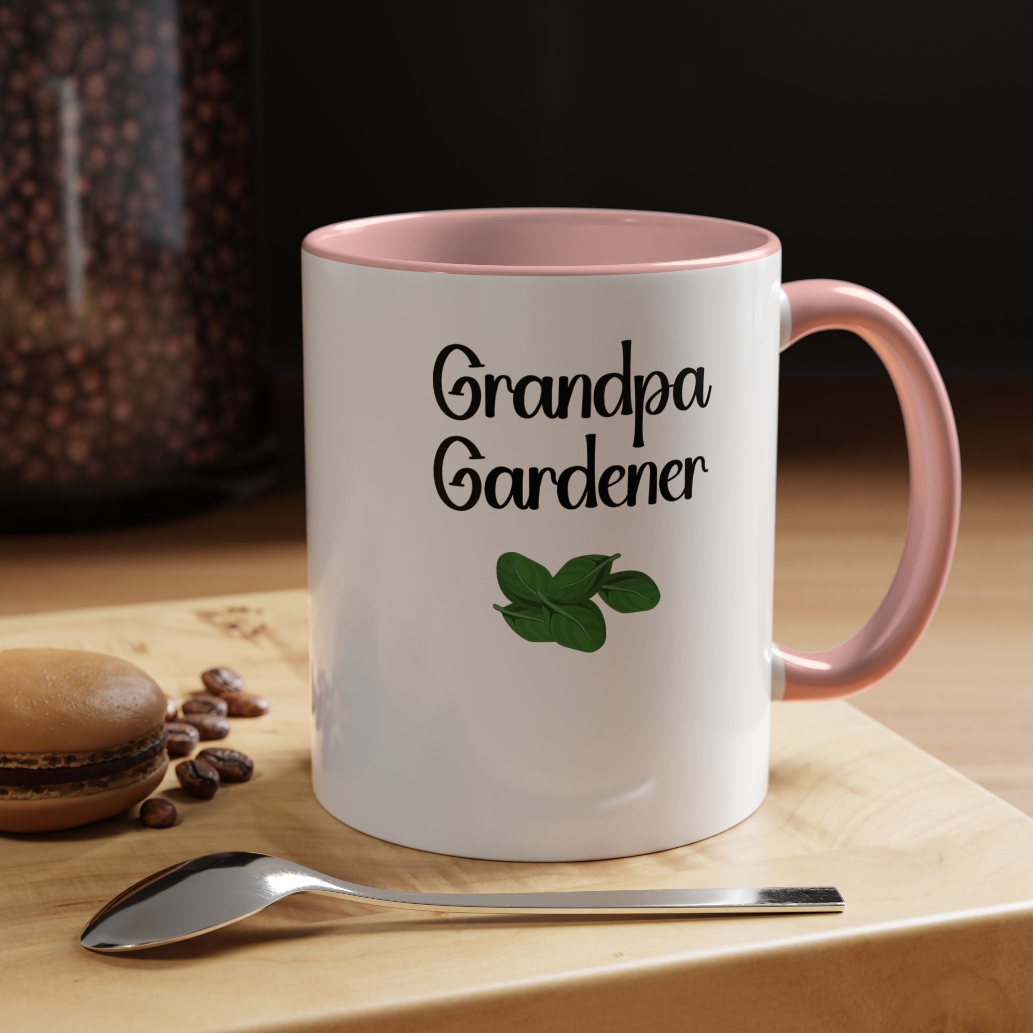 Mug with 'Grandpa Gardener' text and green leaf design on a wooden surface with coffee beans and a spoon.