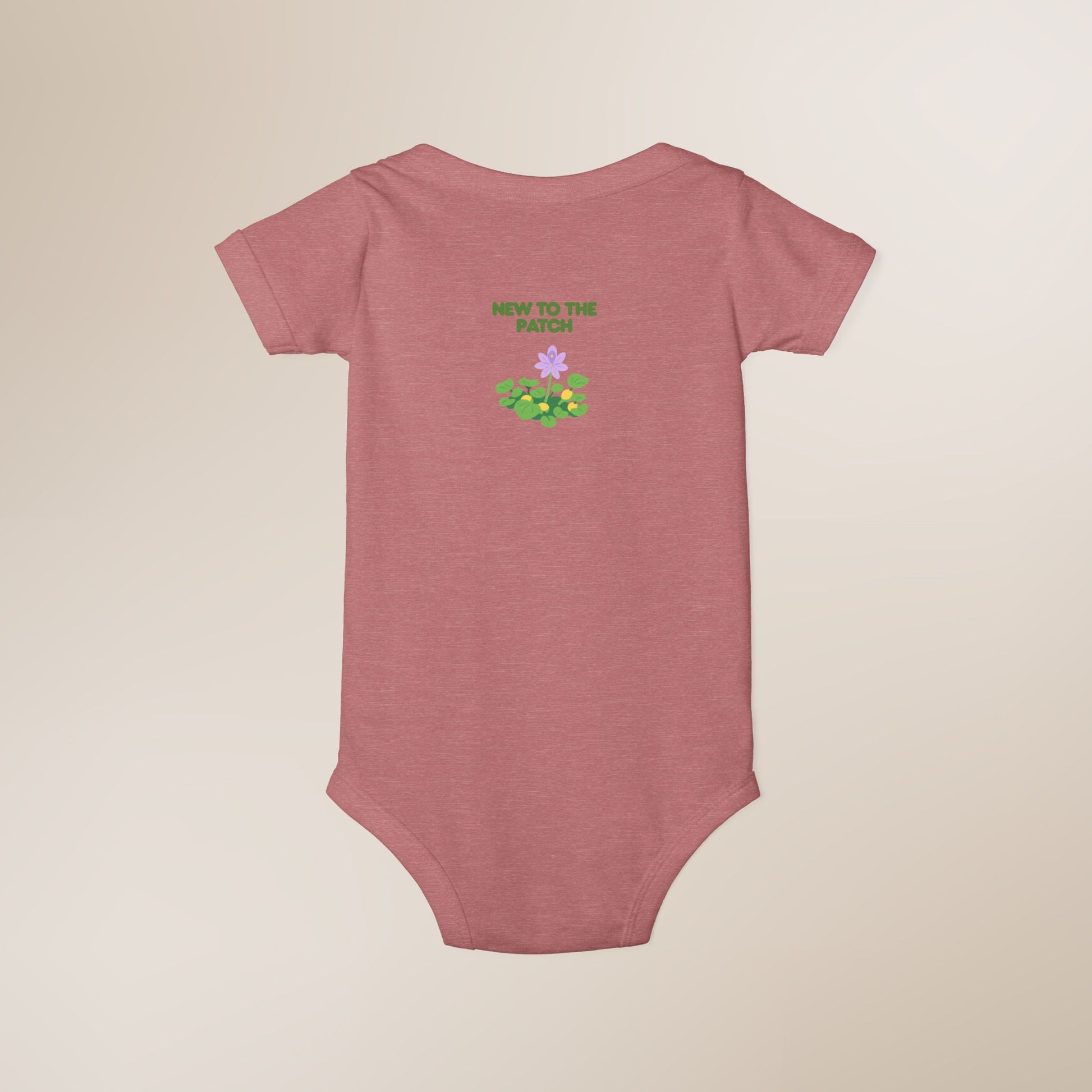 Pink baby onesie with 'New to the Patch' text and floral design on a beige background