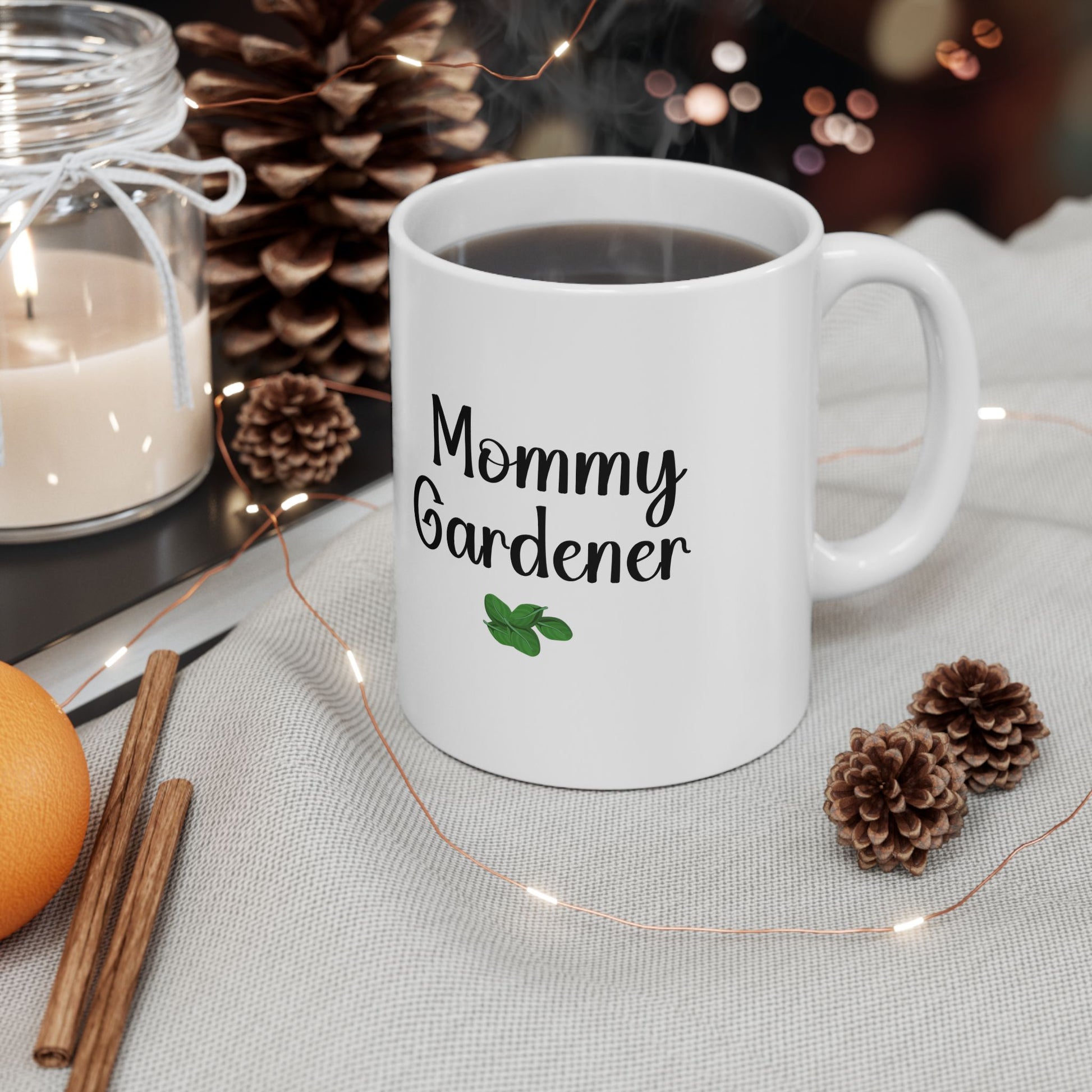 White mug with 'Mommy Gardener' text on a table with decorative items