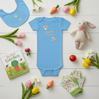 Blue baby onesie with floral design and text, surrounded by gardening-themed items on a wooden surface.