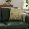 Decorative pillow with nature design on a green sofa in a living room setting.