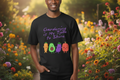Person wearing a black sweatshirt with colorful vegetables and text in a garden setting