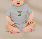 Baby wearing a gray onesie with 'New to the Patch' text and graphics on a beige background