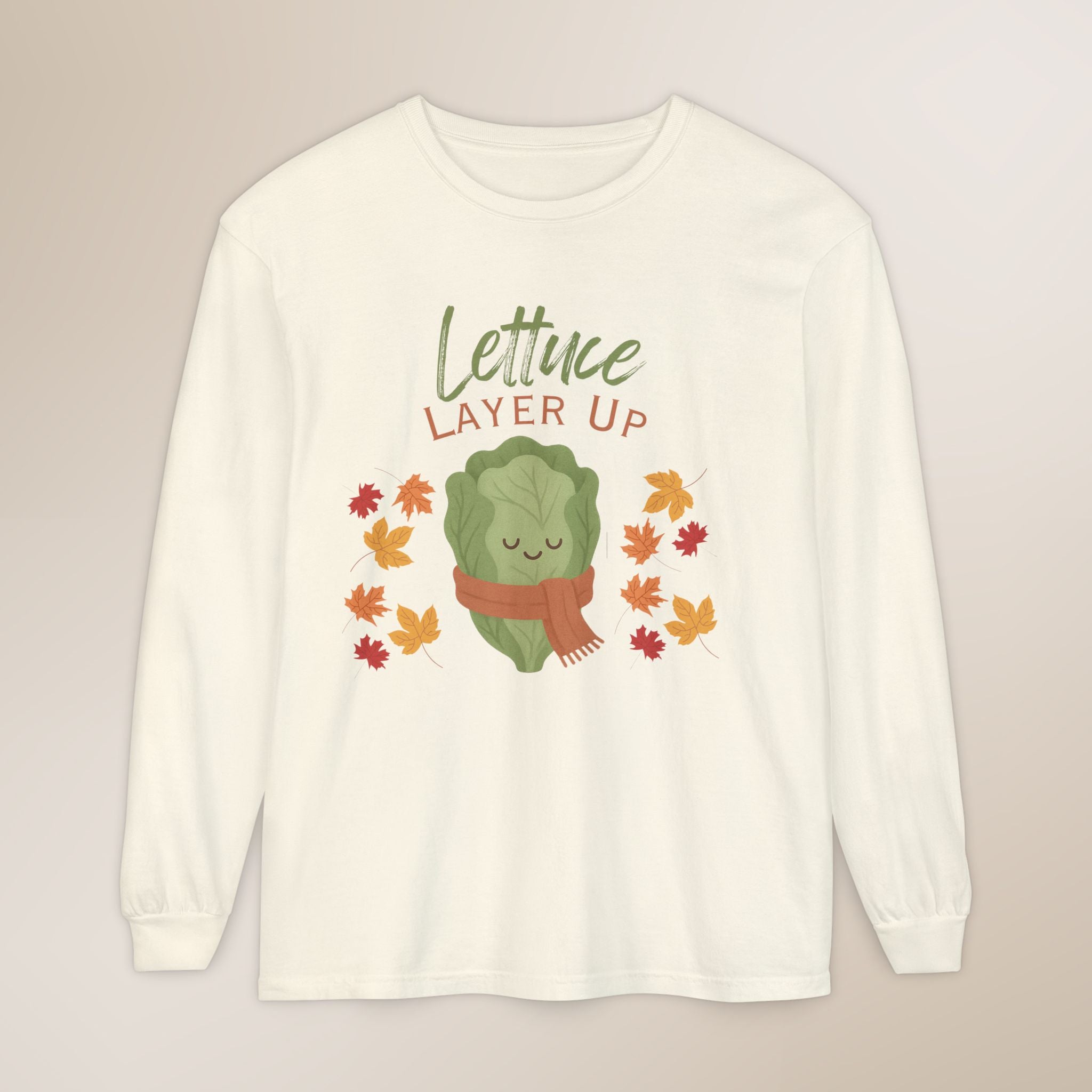 White long-sleeve shirt with a cartoon lettuce character and 'Lettuce Layer Up' text on a beige background