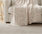 Floral-patterned blanket draped over a white sofa in a living room.
