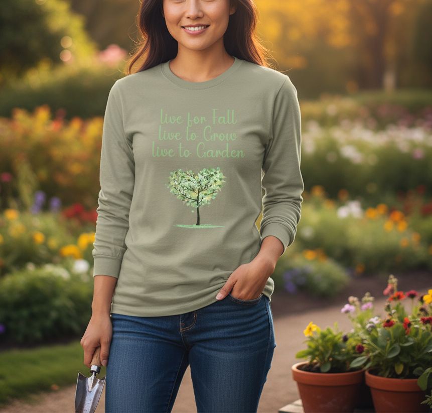 Woman wearing a green long-sleeve shirt with a tree design and text, standing in a garden.