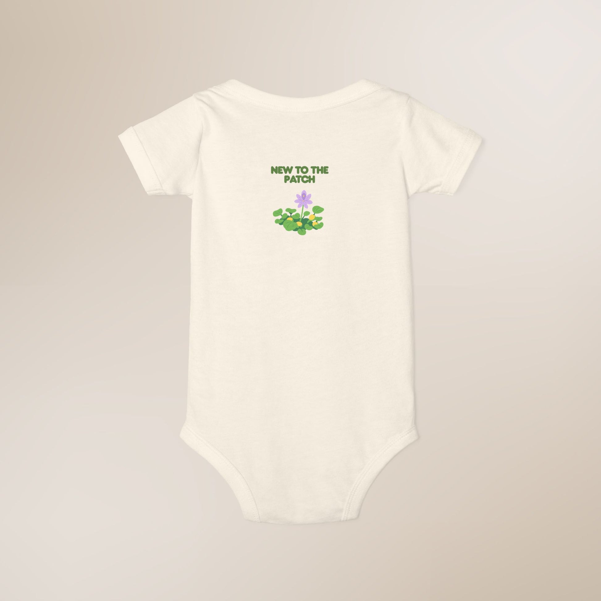 White baby onesie with 'New to the Patch' text and floral design on a beige background