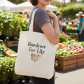 Person holding a tote bag with 'Gardener For Life' text at an outdoor market.