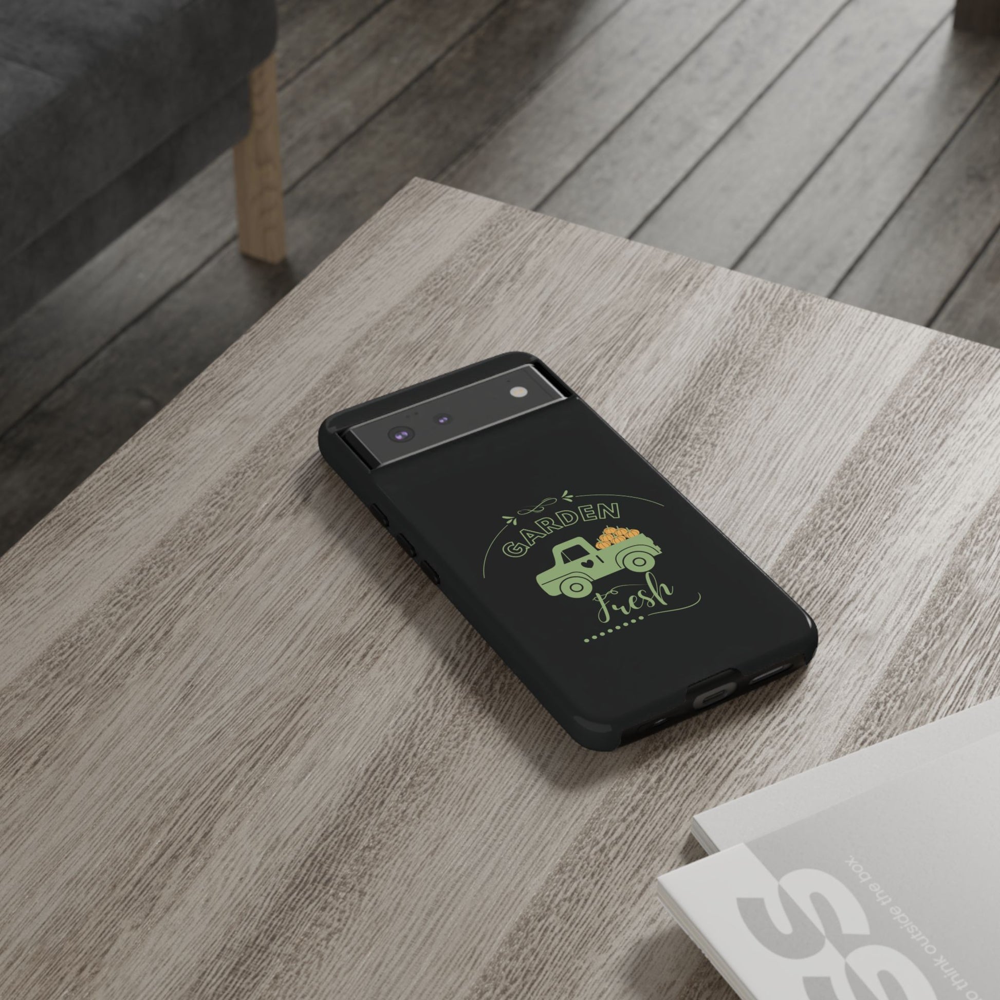 Black phone case with a green truck design on a wooden surface