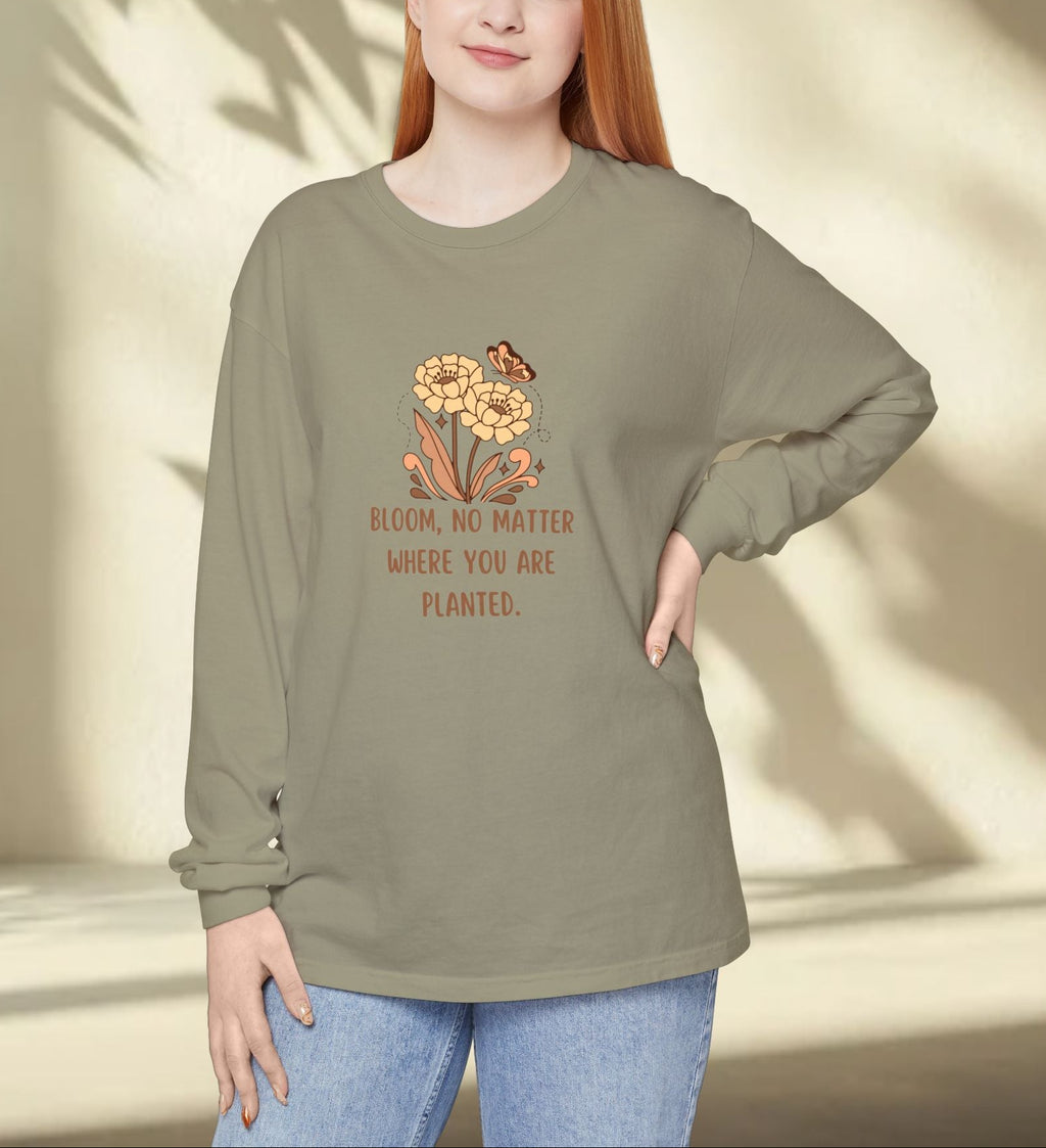 Woman wearing a green long-sleeve shirt with a floral design and text, standing against a neutral background.