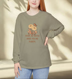 Woman wearing a green long-sleeve shirt with a floral design and text, standing against a neutral background.