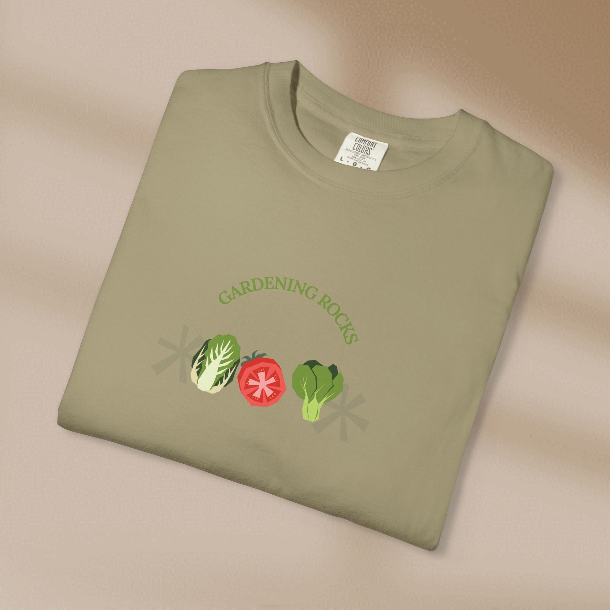 Folded green t-shirt with 'Gardening Rocks' text and vegetable graphics on a beige background