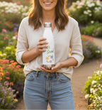 Woman holding a water bottle with a garden-themed design in a garden setting