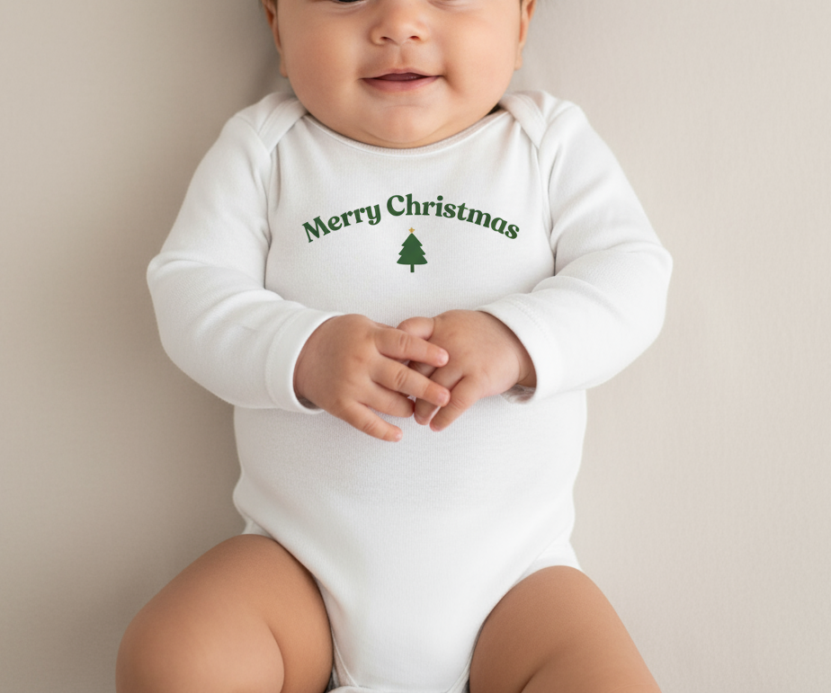 Baby wearing a white onesie with 'Merry Christmas' text and tree graphic.