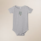 Gray baby onesie with 'Grow a Little, Cheer a Lot' text on a beige background