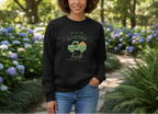 Person wearing a black sweatshirt with a graphic design in a garden setting