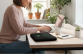 Woman using a laptop at a desk with plants in the background