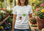 Person wearing a white t-shirt with a gardening graphic and text, standing in a garden setting.
