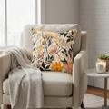 Beige armchair with a floral pillow and blanket in a cozy living room setting.