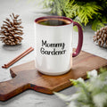 Mug with 'Mommy Gardener' text on a wooden board with pinecones and cinnamon sticks.