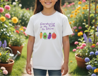 Young girl wearing a t-shirt with gardening-themed design in a garden setting