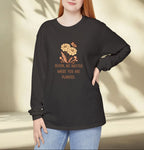 Woman wearing a black long-sleeve shirt with a floral design and text, standing against a neutral background.