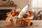 White water bottle with 'Fall into Carving' design in a basket with autumn-themed decorations on a wooden surface.