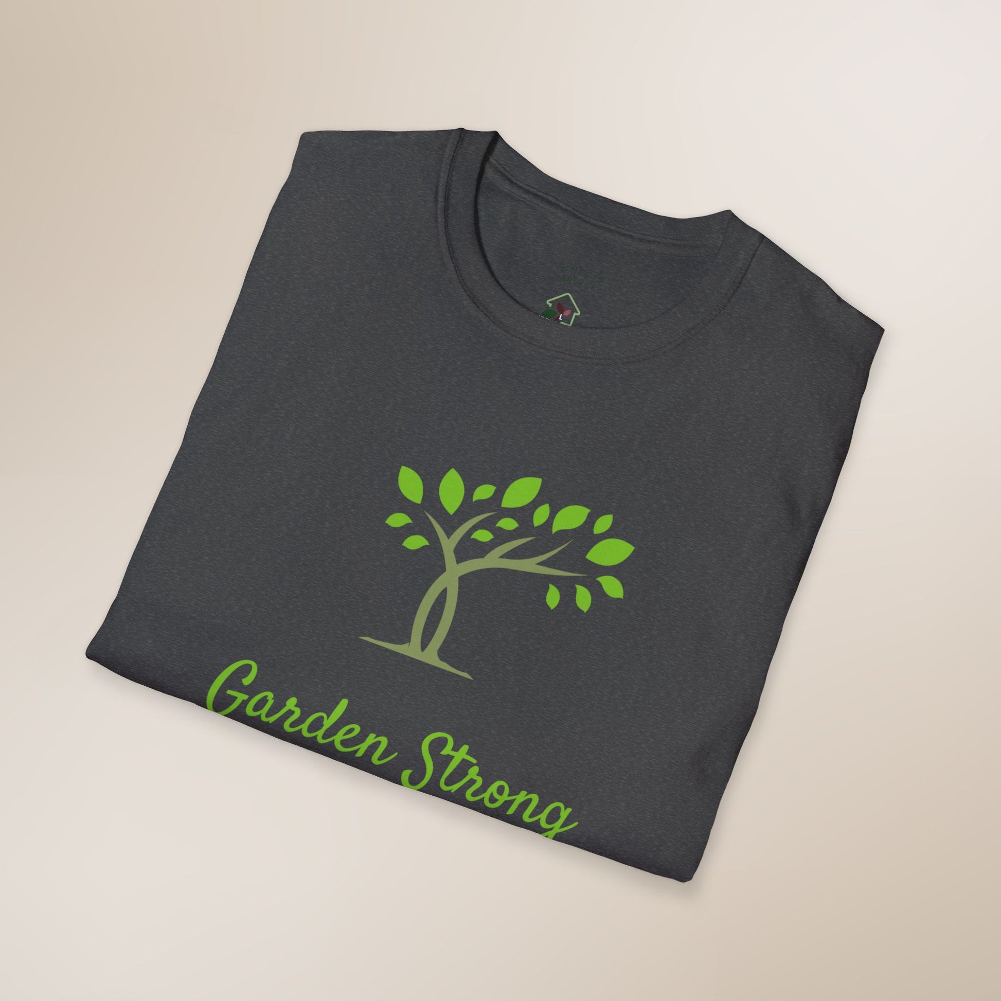 Folded dark gray t-shirt with green tree and 'Garden Strong' text on a beige background