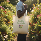 Person holding a tote bag with 'Daddy Gardener' text in a garden setting