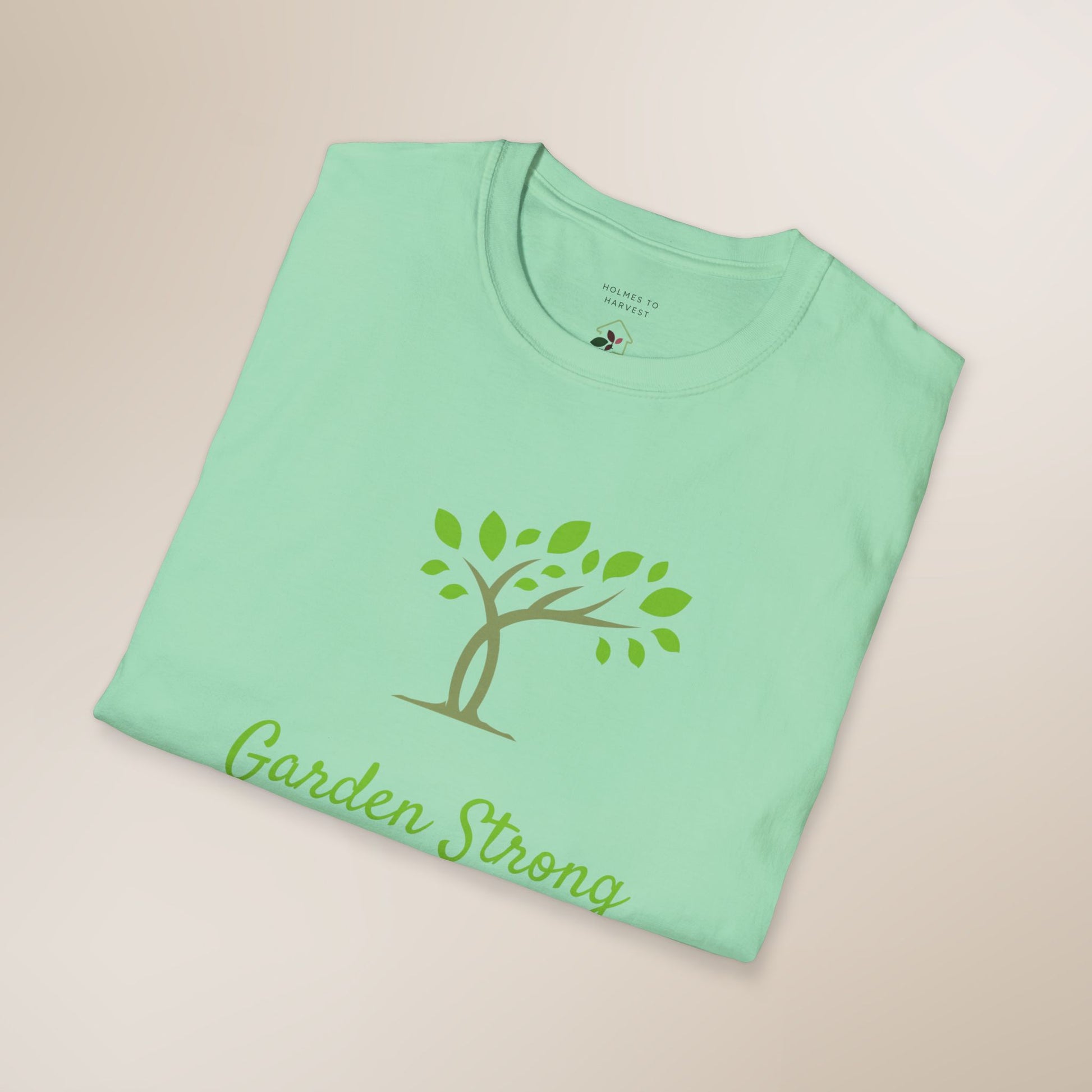 Folded green t-shirt with 'Garden Strong' design on a beige background