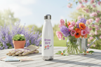 White water bottle with 'Grow Girl!' text on a table with flowers and gardening tools