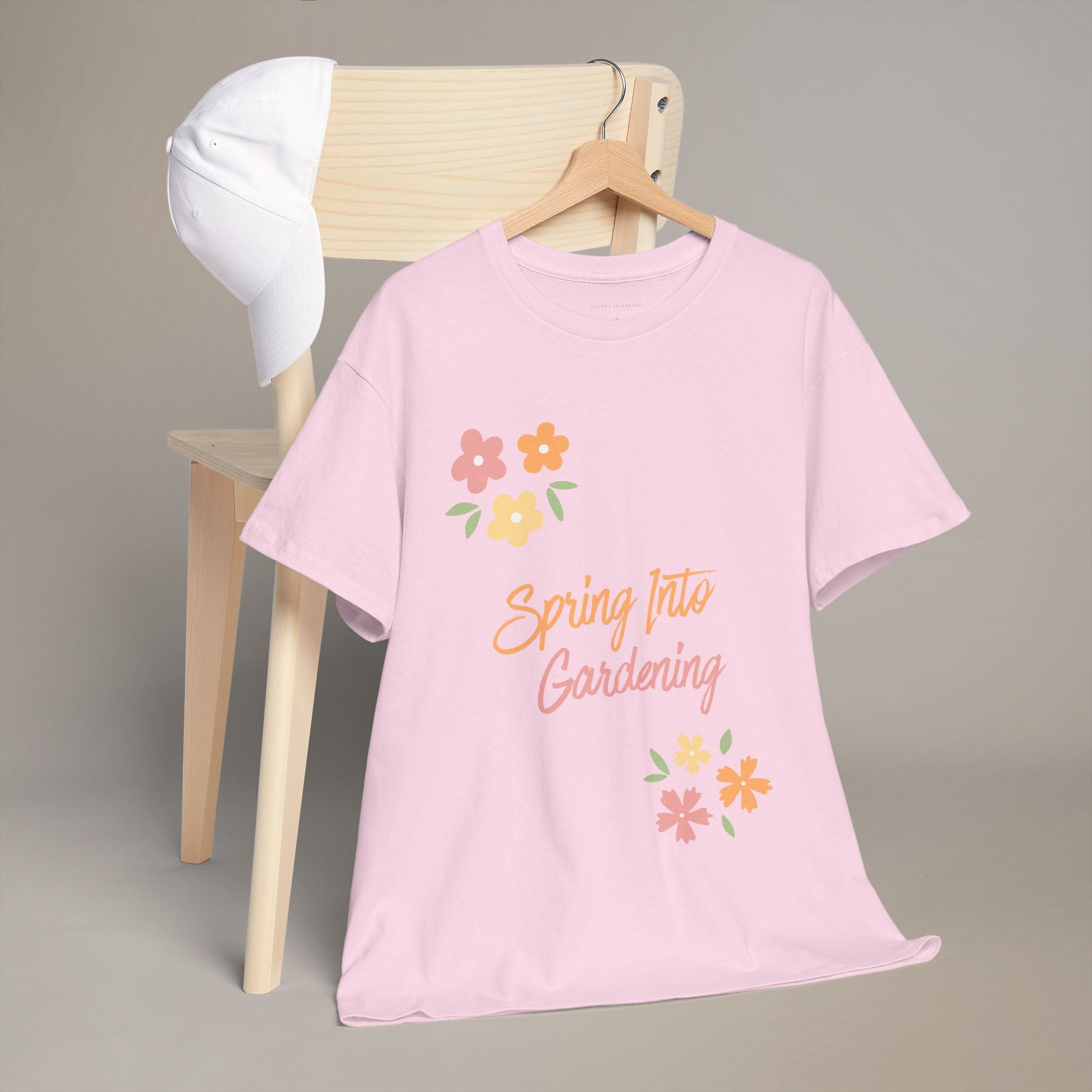 Pink t-shirt with 'Spring Into Gardening' text and floral designs on a wooden chair.
