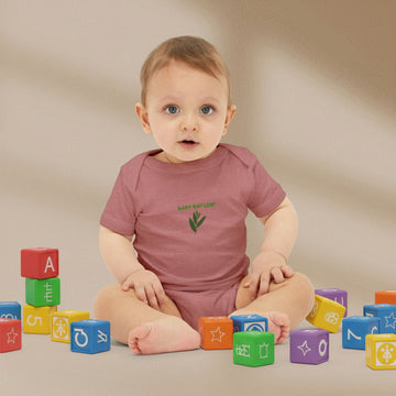 Baby wearing a pink onesie with a green logo on a beige background