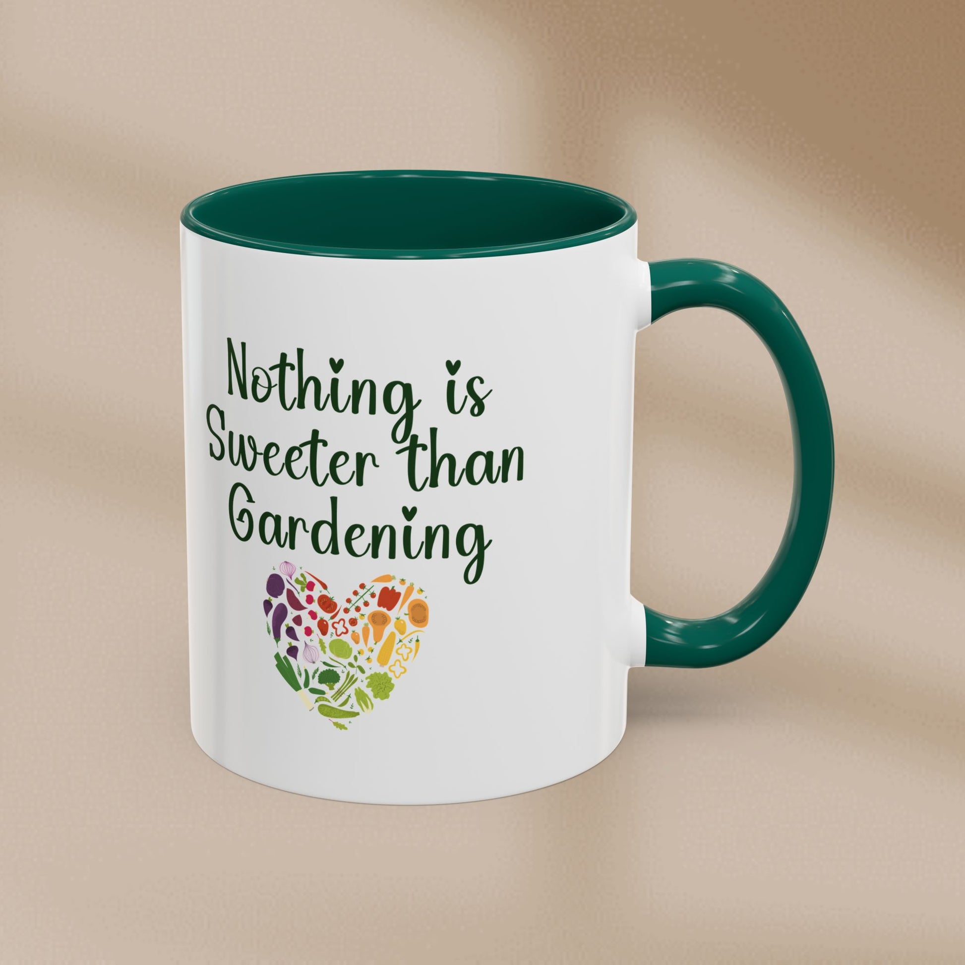 White mug with green interior and handle, featuring 'Nothing is Sweeter than Gardening' text and a colorful heart design on a beige background.