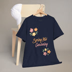 Green t-shirt with 'Spring Into Gardening' text and flowers on a wooden chair.