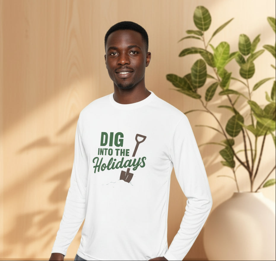 Man wearing a white long-sleeve shirt with 'Dig into the Holidays' text, standing in front of a plant.