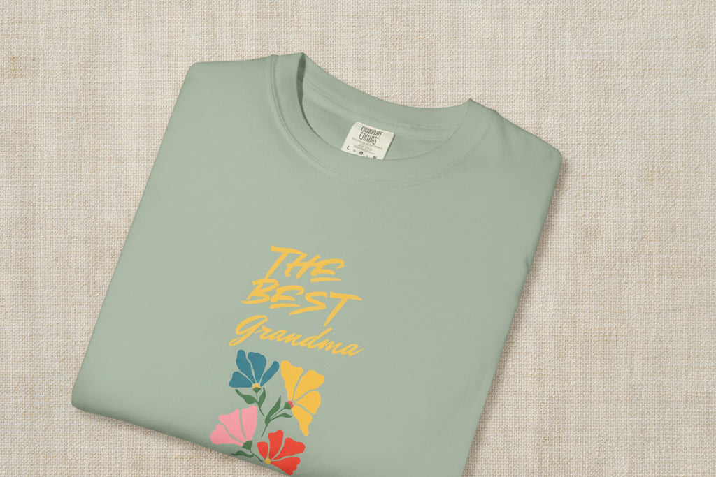Folded green t-shirt with colorful floral design and text on a beige background
