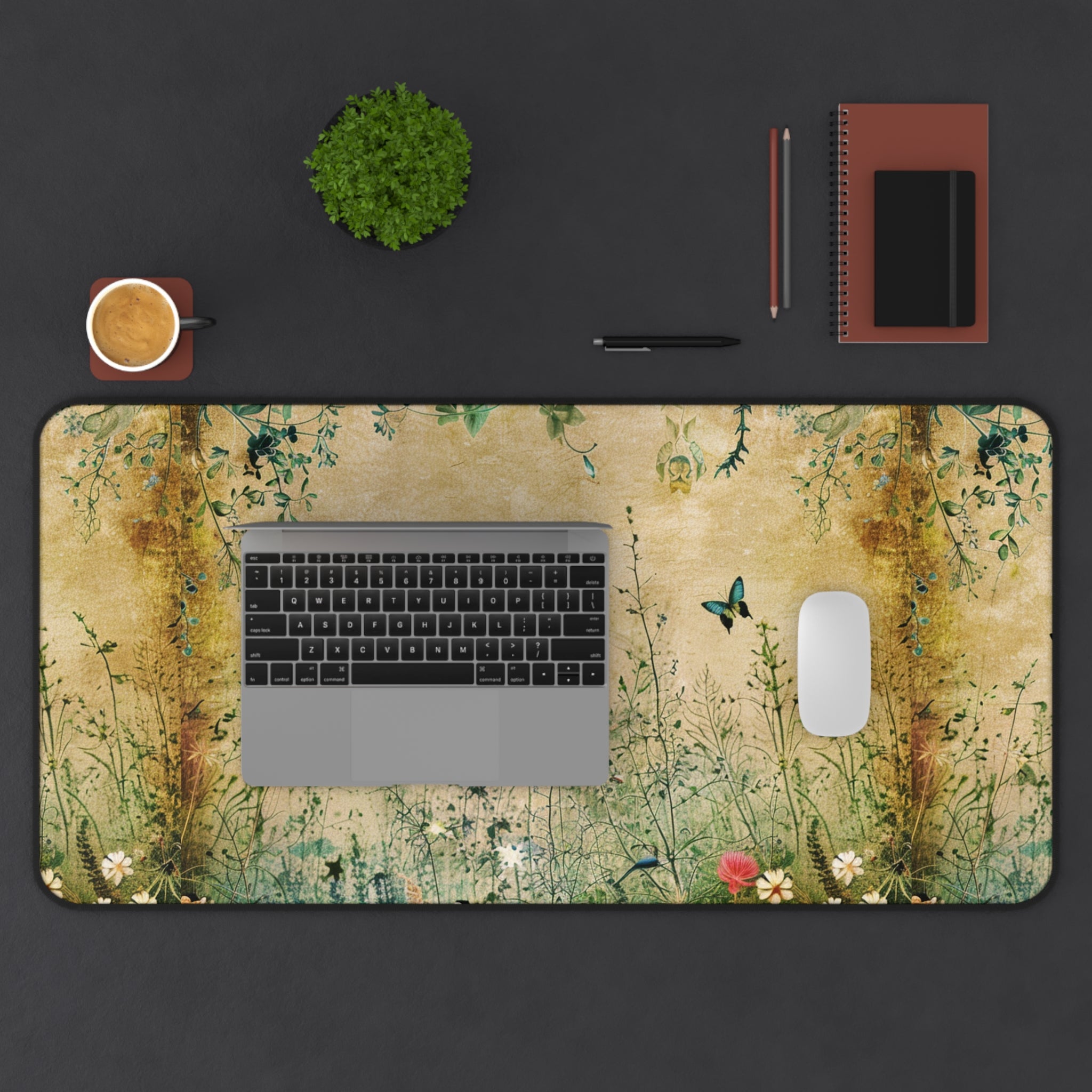 Desk setup with a laptop on a decorative desk mat featuring nature-themed design.