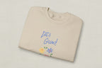 Beige sweatshirt with 'Let's Grow!' text and floral designs on a white background