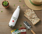 Gardening-themed items including a water bottle, gloves, trowel, and seed packets on a wooden surface.