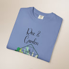 Folded blue t-shirt with 'Rise & Garden' text and green graphic on a beige background