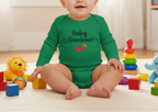 Baby wearing a green 'Baby Gardener' onesie surrounded by colorful toys on a light wooden floor.