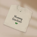 Folded beige t-shirt with 'Mommy Gardener' text on a beige background