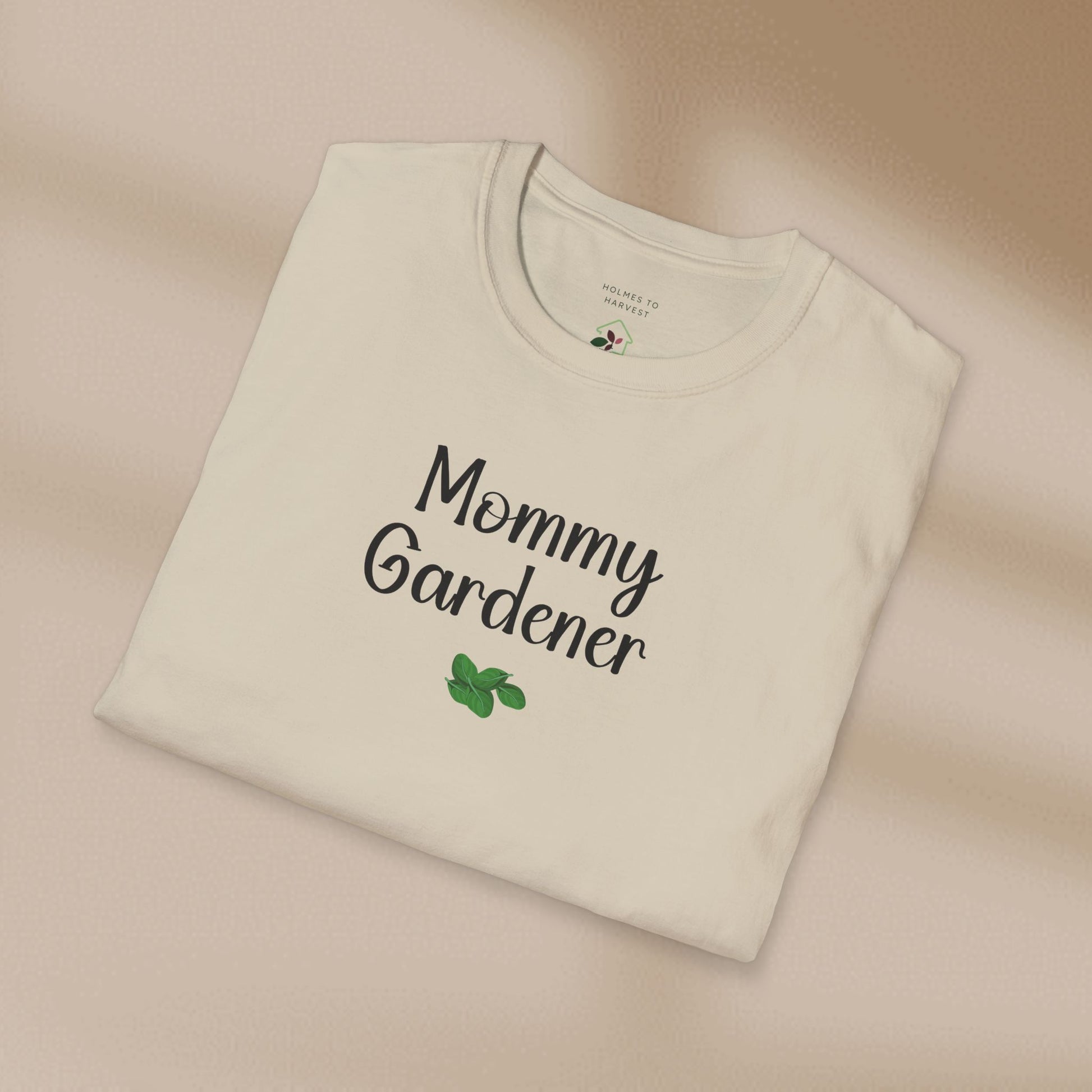 Folded beige t-shirt with 'Mommy Gardener' text on a beige background
