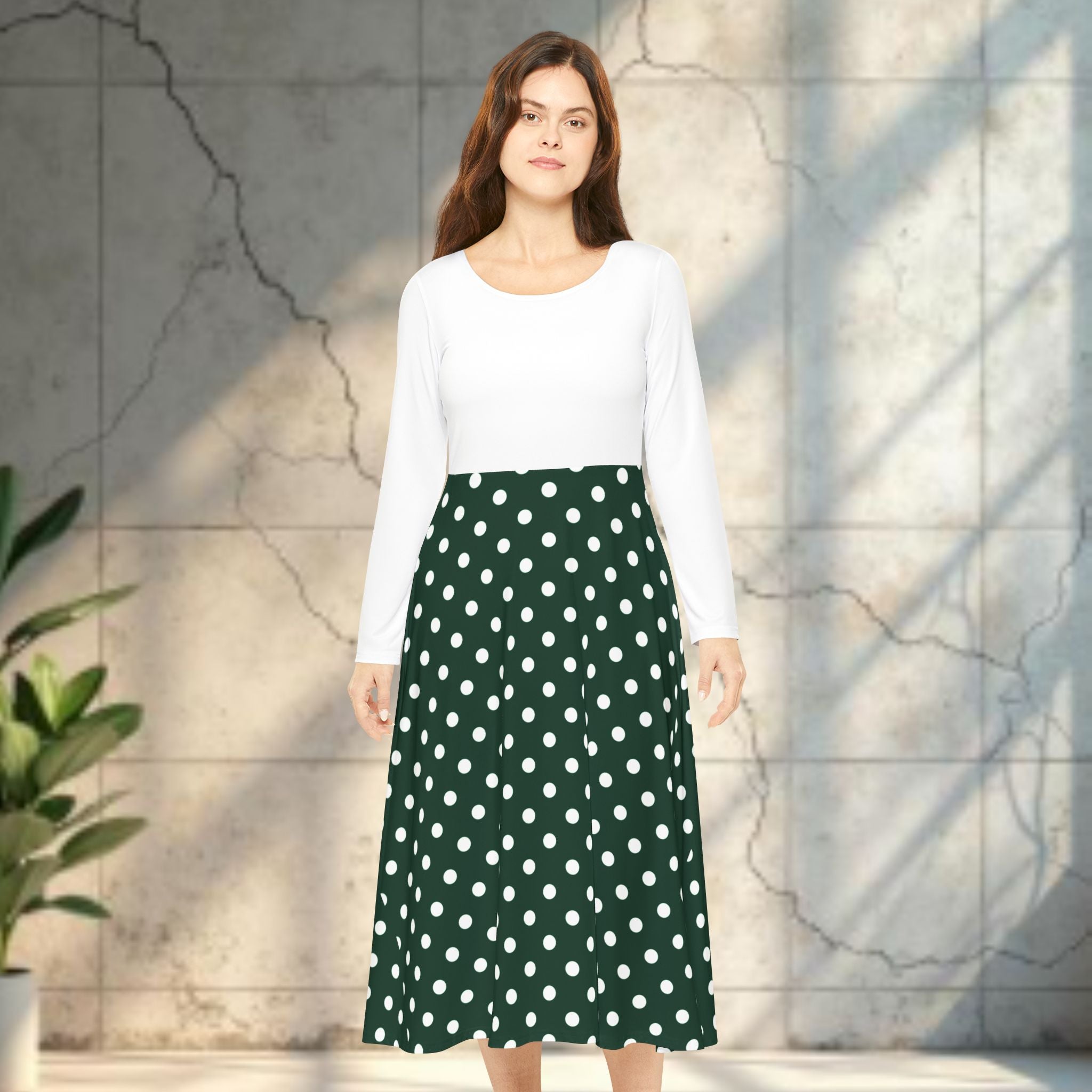 Woman wearing a white top and green polka dot skirt standing against a light stone wall.