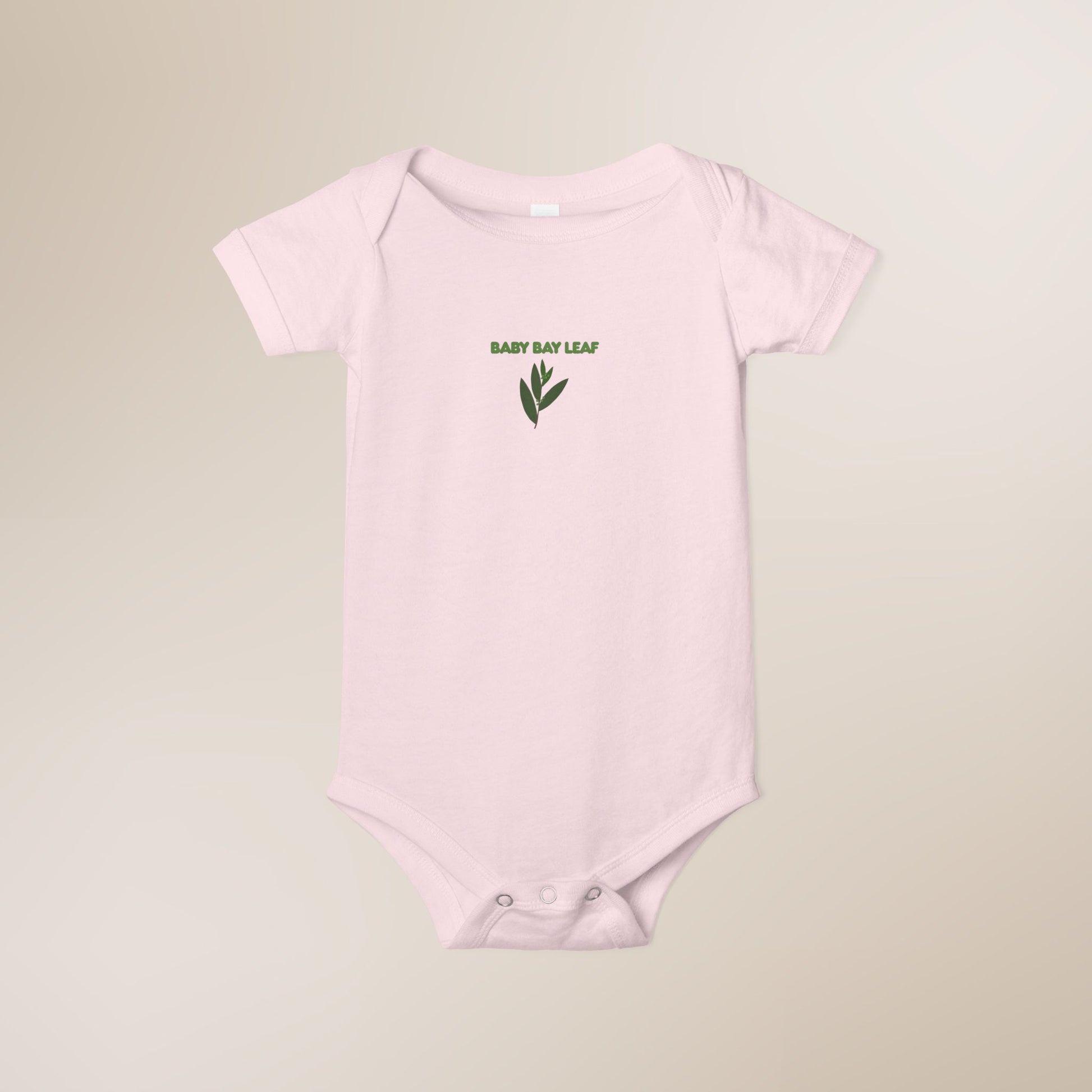 Pink baby onesie with 'Baby Bay Leaf' text and leaf graphic on a beige background