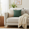 Beige sofa with a green polka dot pillow and beige blanket in a living room setting.